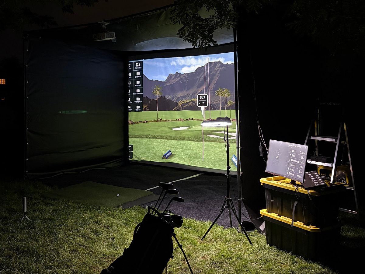 The TILT enclosure lit up at night, with the course on screen and the leaderboard on a monitor